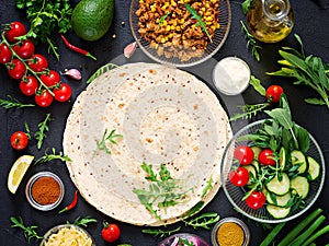 Ingredients for burritos wraps with beef and vegetables on black background.