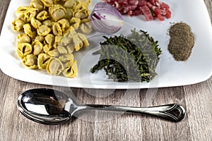 Ingredients for cappelletti pancetta and asparagus in a plate with parmesan
