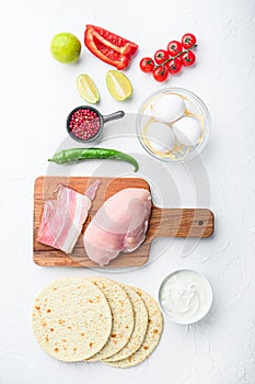 Ingredients for chicken tacos, , tomatoes, corn, egg, pepper,lime chicken meat and tortillas over white textured background top