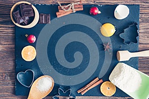 Ingredients for Christmas, winter baking cookies. Flour, cranberries, dried oranges, cinnamon, spices on a black stone table, top