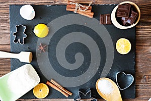 Ingredients for Christmas, winter baking cookies. Flour, cranberries, dried oranges, cinnamon, spices on a black stone table, top