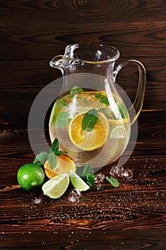 Ingredients for a citrus lemonade on a wooden background. Lime, oranges, mint next to a jar of fruit juice. Cafe drinks.