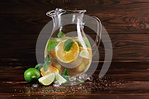 Ingredients for a citrus lemonade on a wooden background. Lime, oranges, mint next to a jar of fruit juice. Cafe drinks.