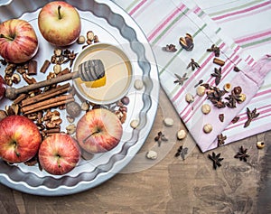 Ingredients for cooking baked apples with nuts honey are on the tablecloth and in the baking dish, on a rustic background, a p