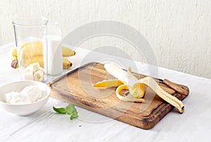 Ingredients for cooking banana milkshake on white wooden table