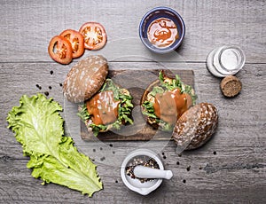 Ingredients for cooking a burger with chicken and vegetables, peppers, tomatoes, lettuce and salt on wooden rustic background top