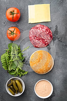 Ingredients for cooking burgers. Raw ground beef meat cutlets, on gray stone background, top view flat lay