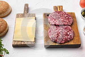 Ingredients for cooking burgers. Raw ground beef meat cutlets, on white stone  background