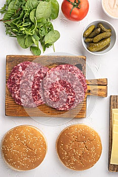 Ingredients for cooking burgers. Raw ground beef meat cutlets, on white stone  background, top view flat lay