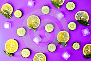 Ingredients for cooking cold spring lemonade drink with cucumber, pieces of lemon, fresh leaves mint ice cubes on blue background
