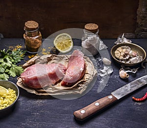 Ingredients for cooking concept Preparation of two steak of turkey lemon herb seasoning garlic hot red pepper and knife wooden