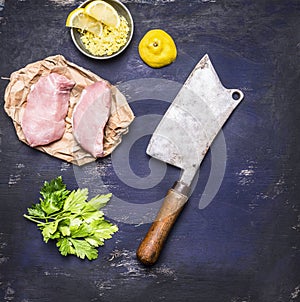 Ingredients for cooking concept Slasher 2 chicken meat steak on paper grated lemon on dark blue rustic wooden background top view