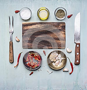 Ingredients for cooking cutting board, fork and knife for meat, hot red pepper bowl of garlic butter and seasonings rust