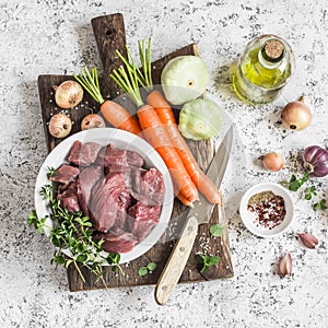 Ingredients for cooking dinner - raw beef meat, carrots, squashes, onions, garlic, thyme, spices, olive oil.