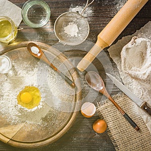 Ingredients for cooking dough or bread. Broken egg on top of a bunch of white rye flour. Dark wooden background.