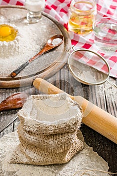 Ingredients for cooking dough or bread. Broken egg on top of a bunch of white rye flour. Dark wooden background.