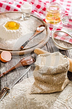 Ingredients for cooking dough or bread. Broken egg on top of a bunch of white rye flour. Dark wooden background.