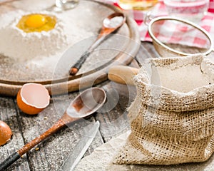 Ingredients for cooking dough or bread. Broken egg on top of a bunch of white rye flour. Dark wooden background.