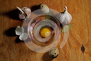 Ingredients for cooking: eggs, garlic, pepper, bay leaves, spices on a wooden background