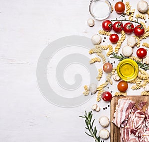 Ingredients for cooking fusilli pasta with bacon vegetables, spices and herbs border, place text on wooden rustic background