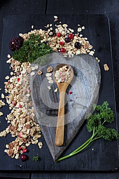 Ingredients for cooking healthy breakfast. Nuts, oat flakes, dried fruits, honey, granola. On dark backgound