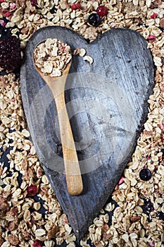 Ingredients for cooking healthy breakfast. Nuts, oat flakes, dried fruits, honey, granola, wooden heart .