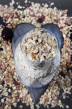 Ingredients for cooking healthy breakfast. Nuts, oat flakes, dried fruits, honey, granola, wooden heart .