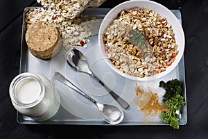 Ingredients for cooking healthy breakfast. Nuts, oat flakes, dried fruits, honey, granola, wooden heart in a white bowl.