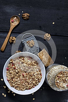 Ingredients for cooking healthy breakfast. Nuts, oat flakes, dried fruits, honey, granola, wooden heart in a white bowl.