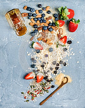 Ingredients for cooking healthy breakfast. Strawberries, blueberries, nuts, oat flakes, dried fruits, honey with