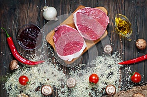 Ingredients for cooking healthy meat dinner. Raw uncooked beef rib eye steaks with mushrooms, rice, herbs and spices on table back