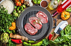 Ingredients for cooking healthy meat dinner. Raw uncooked beef steaks with vegetables, rice, herbs, spices and wine