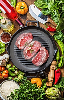 Ingredients for cooking healthy meat dinner. Raw uncooked beef steaks with vegetables, rice, herbs, spices and wine