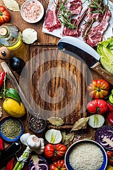 Ingredients for cooking healthy meat dinner. Raw uncooked lamb chops with vegetables, rice, herbs and spices over rustic