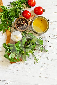 Herbs spices, olive oil and vegetables on a wooden table. Top view flat lay background. Copy space