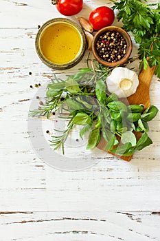 Herbs spices, olive oil and vegetables on a wooden table. Top view flat lay background. Copy space