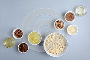 Ingredients for cooking homemade granola: oatmeal, applesauce, honey, oil, almond, walnut, raisin, flax and sesame seeds