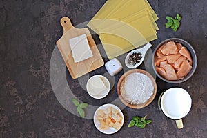 Ingredients for cooking lasagna with salmon: slices of raw salmon, mozzarella cheese, milk, parmesan cheese, wheat flour, dried