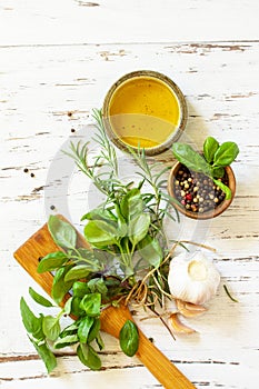 Ingredients for cooking. Olive oil, garlic and herbs on a white wooden table. Top view flat lay background.