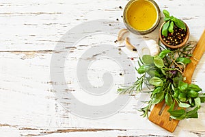 Ingredients for cooking. Olive oil, garlic and herbs on a white wooden table. Top view flat lay background.