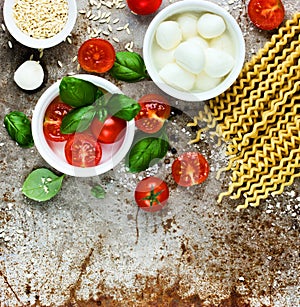 Ingredients for cooking pasta caprese - fresh basil, cherry tomatoes, baby mozzarella cheese, fresh pasta fusilli lunghi and