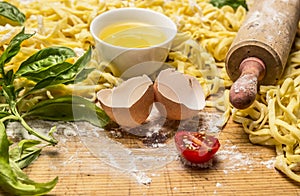 Ingredients for cooking pasta, rolling pin ,egg, herbs,wheat flour wooden background close up