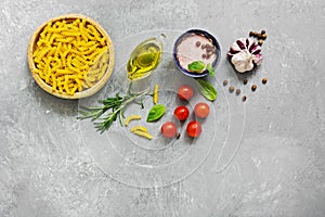 Ingredients for cooking pasta with tomato sauce. Fusilli, tomatoes, basil, olive oil, pink salt, pepper, rosemary and garlic on a