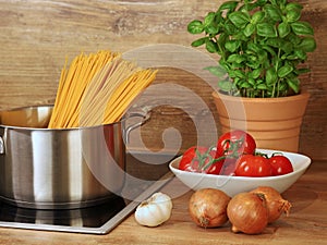 ingredients for cooking pasta with tomato sauce at home, saucepan with raw pasta on stove