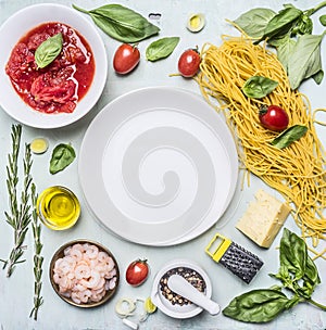 Ingredients for cooking pasta, tomatoes in own juice, basil, shrimp, grater, cherry tomatoes, laid around a white plate place