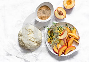 Ingredients for cooking peach mini pies - dough, fresh peaches, thyme, cane sugar on a light background, top view