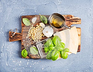 Ingredients for cooking Pesto sauce. Parmesan cheese, metal grater, fresh basil, olive oil, garlic and pine nuts on old