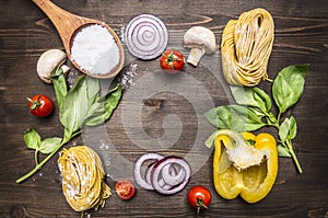 Ingredients for cooking raw pasta with mushrooms, peppers, basil and onions on wooden rustic background top view close up border,