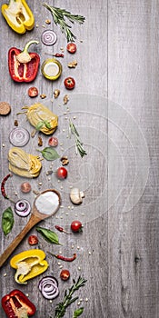 Ingredients for cooking raw pasta with tomatoes, pepper, a wooden spoon, salt, oil, pine nuts and herbs on wooden rustic backgroun
