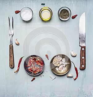 Ingredients for cooking, seasoning, oil, knife, fork, garlic, hot red pepper, lined frame on wooden rustic background top view clo